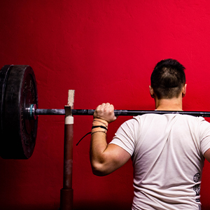man standing with barbell on his shoulders